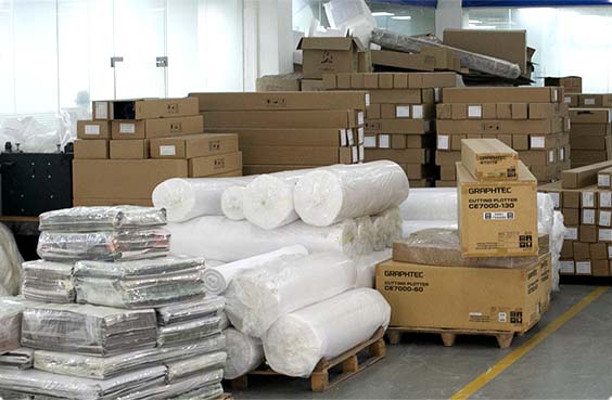 Wrapped fabric rolls and packing cartons stacked on pallets in the AISNUG warehouse