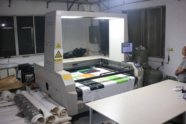 Digital textile printer printing colourful custom designs onto white fabric panels in the AISNUG factory