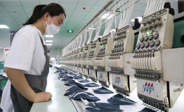 AISNUG operator running a multi-head Tajima embroidery machine producing custom logo shirts